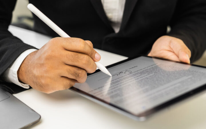 Person unterschreibt ein Dokument auf einem Tablet mit einem digitalen Stift.